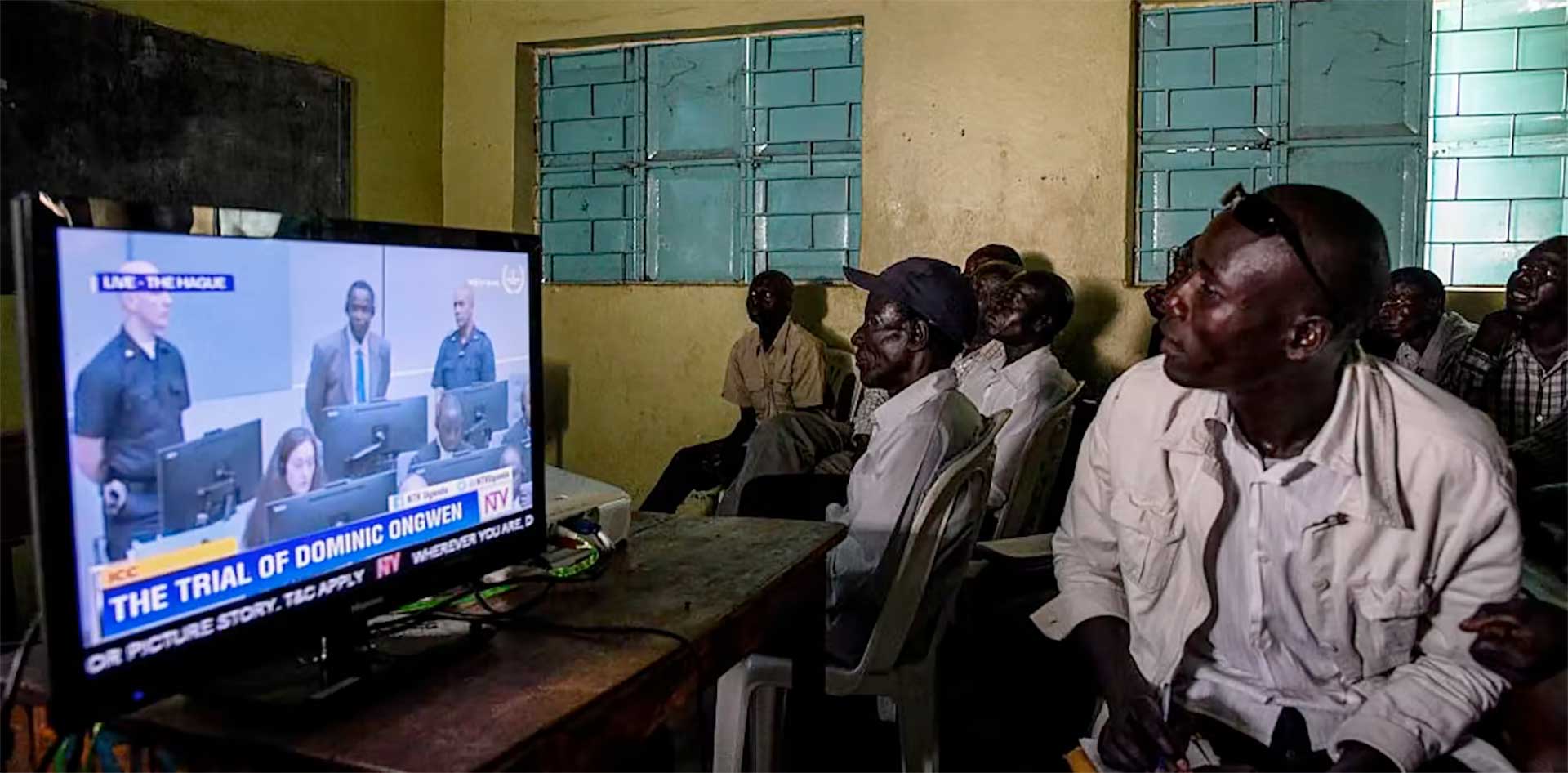 Ugandans watch the start of the International Criminal Court trial of former child soldier-turned-warlord Dominic Ongwen. Isaac Kasamani/AFP via Getty Images