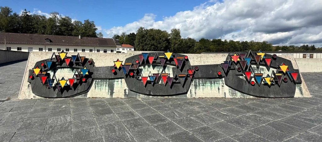  Created by Yugoslav sculptor Nandor Glid, and inaugurated in 1968, the central monument includes a chain-link relief symbolizing prisoner solidarity. The relief displays various colored triangular identification badges that the SS forced inmates to wear, representing categories like political prisoners (red) and Jehovah's Witnesses (purple).